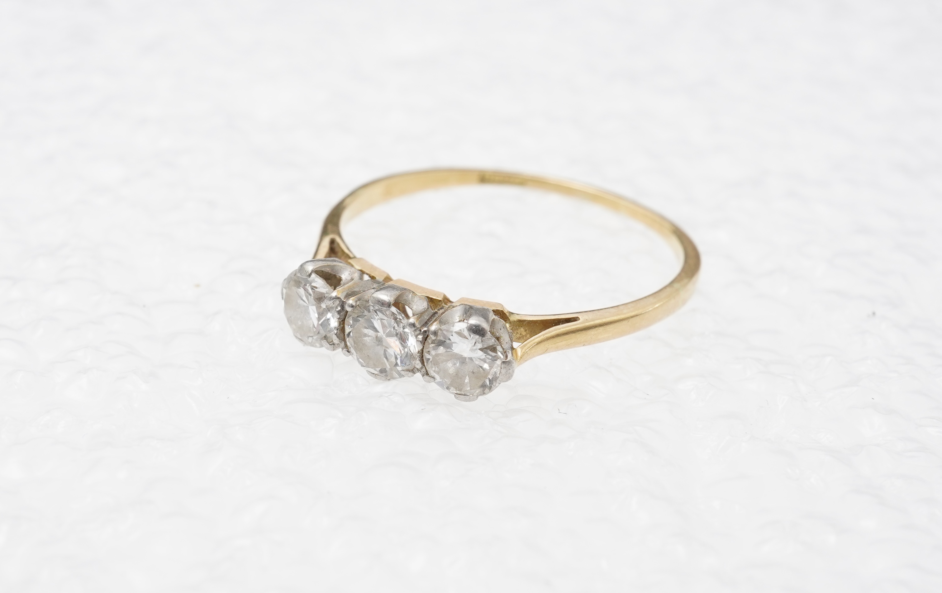 A diamond three-stone ring, set with three circular-cut diamonds totalling approximately 0.50 carats, mounted in gold, size O, stamped 18CT, gross weight approximately 2 grams